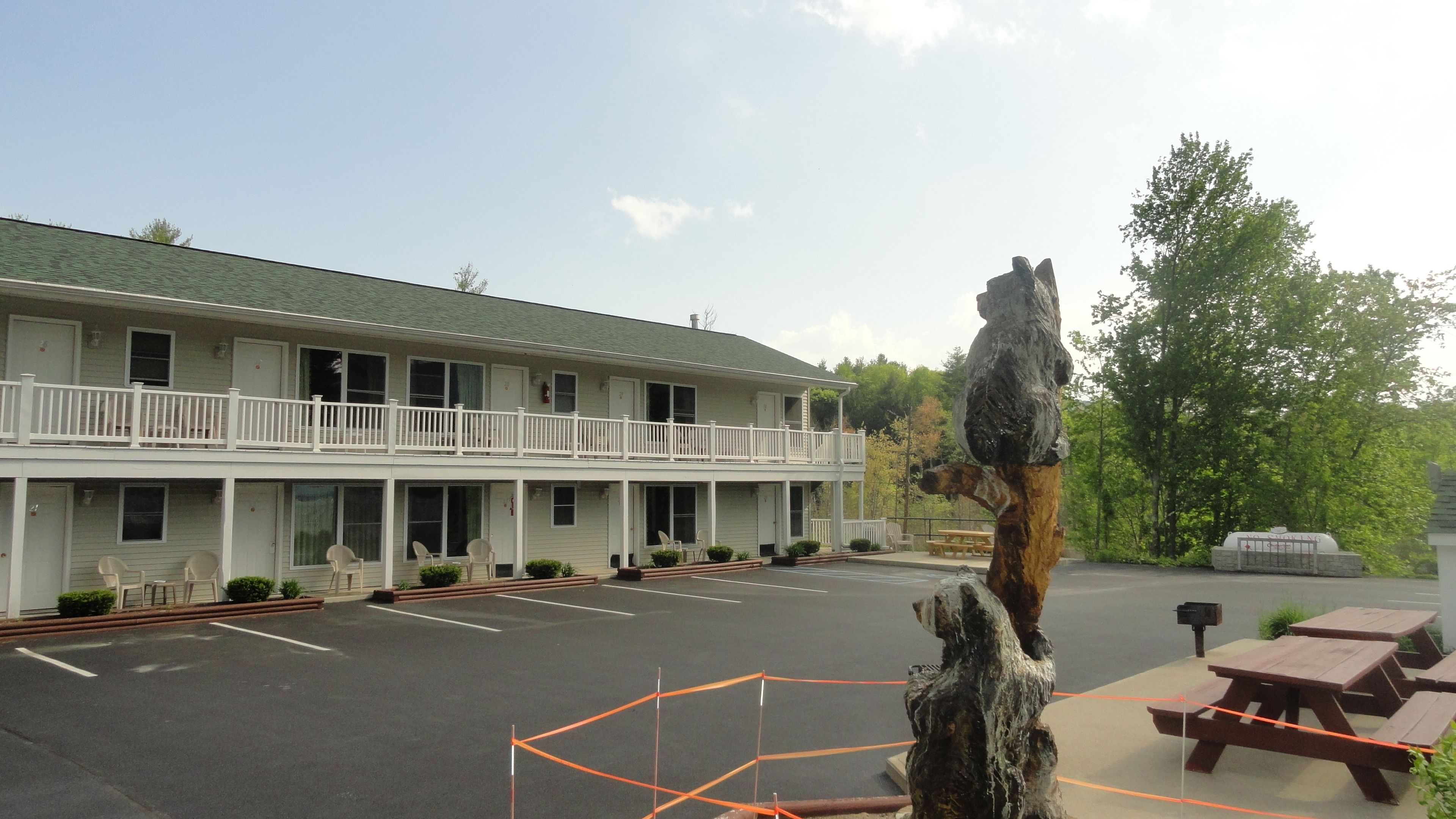 A motel with a two-story structure, a fenced parking area, and picnic tables.