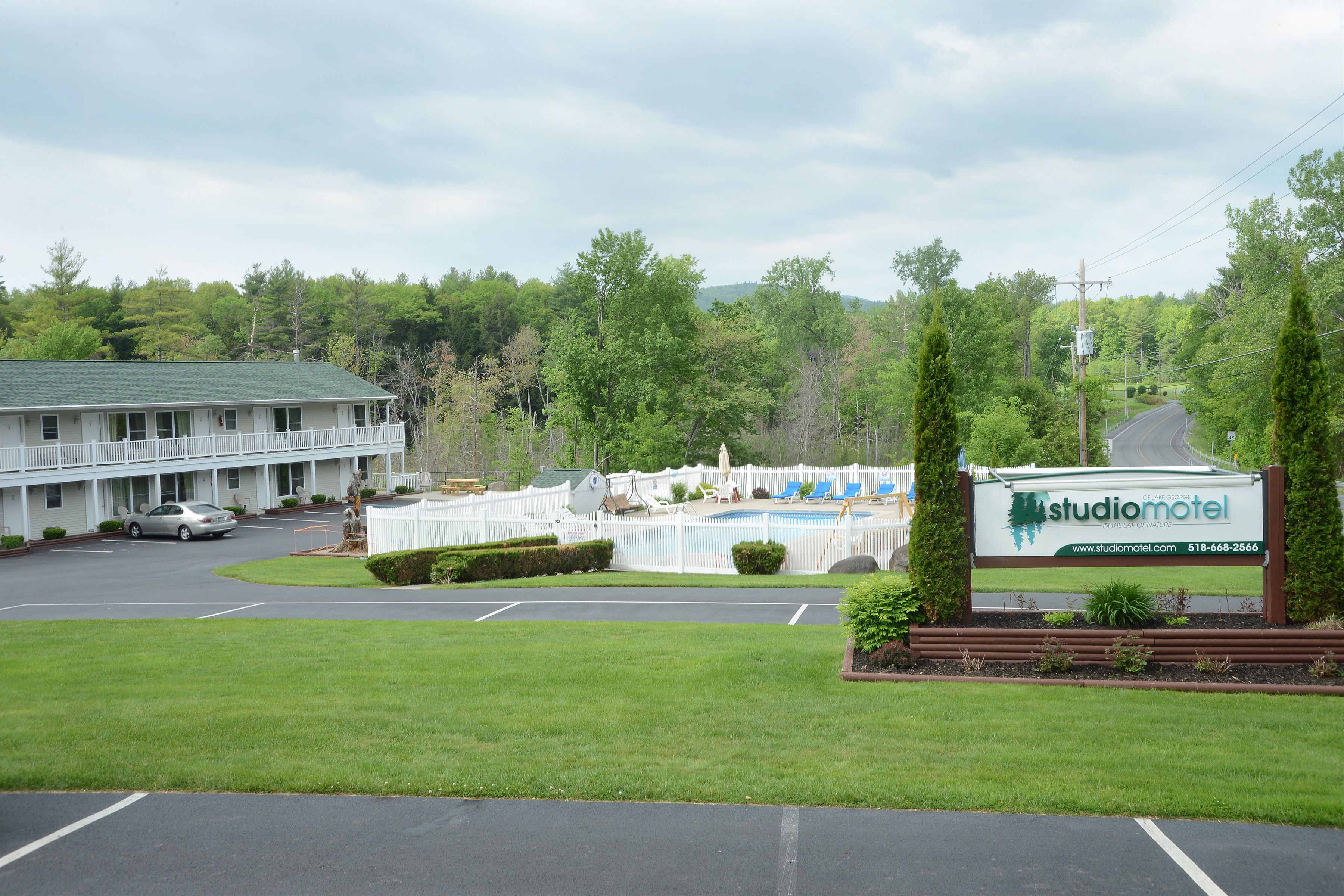 A motel with a swimming pool, a covered patio, and a parking lot.