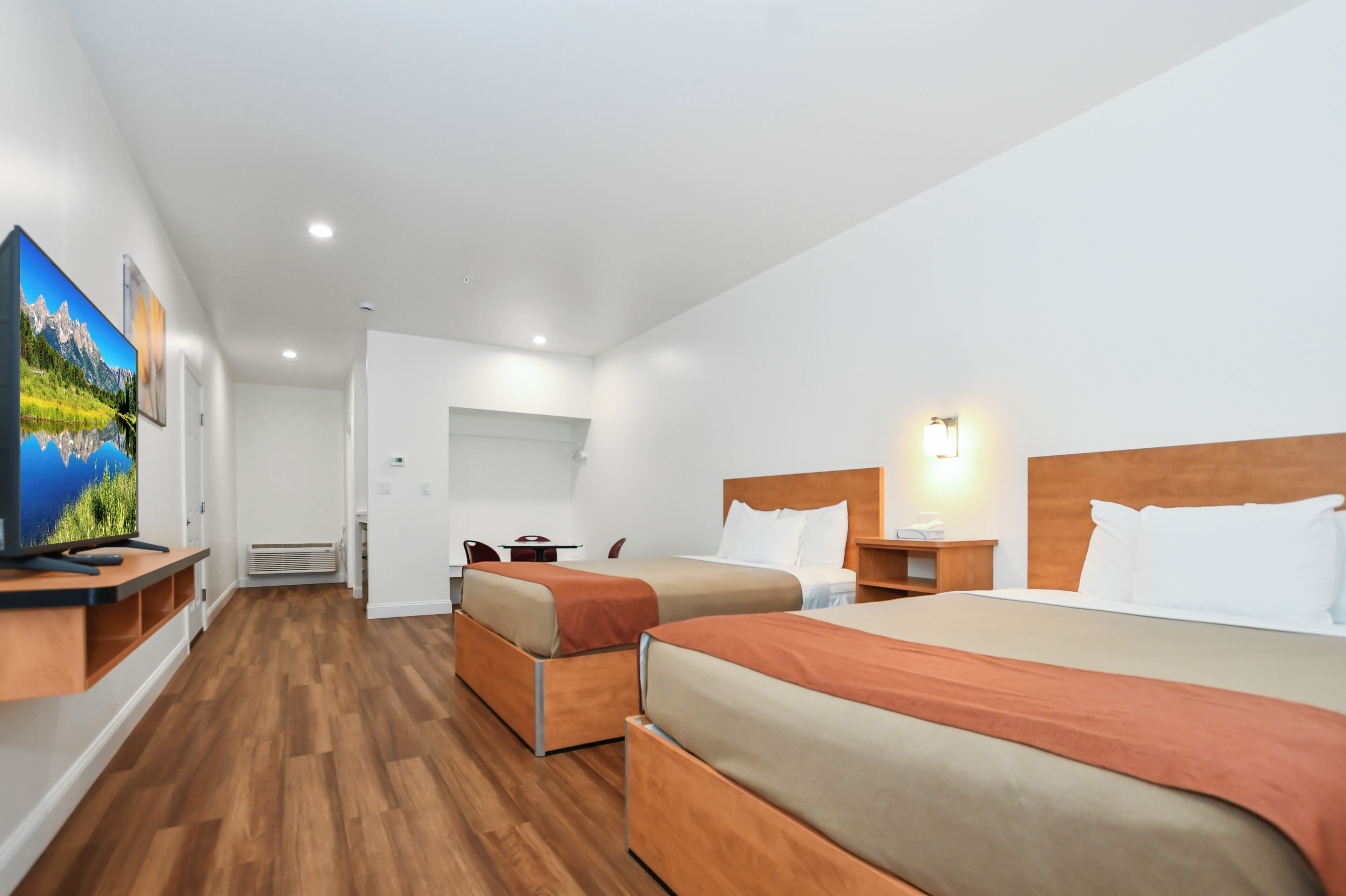 A hotel room with two beds, a TV, and a desk.