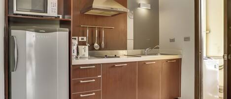 A compact kitchen with a microwave, refrigerator, and sink.