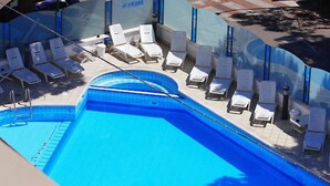 Una piscina con lettini e un ombrellone.