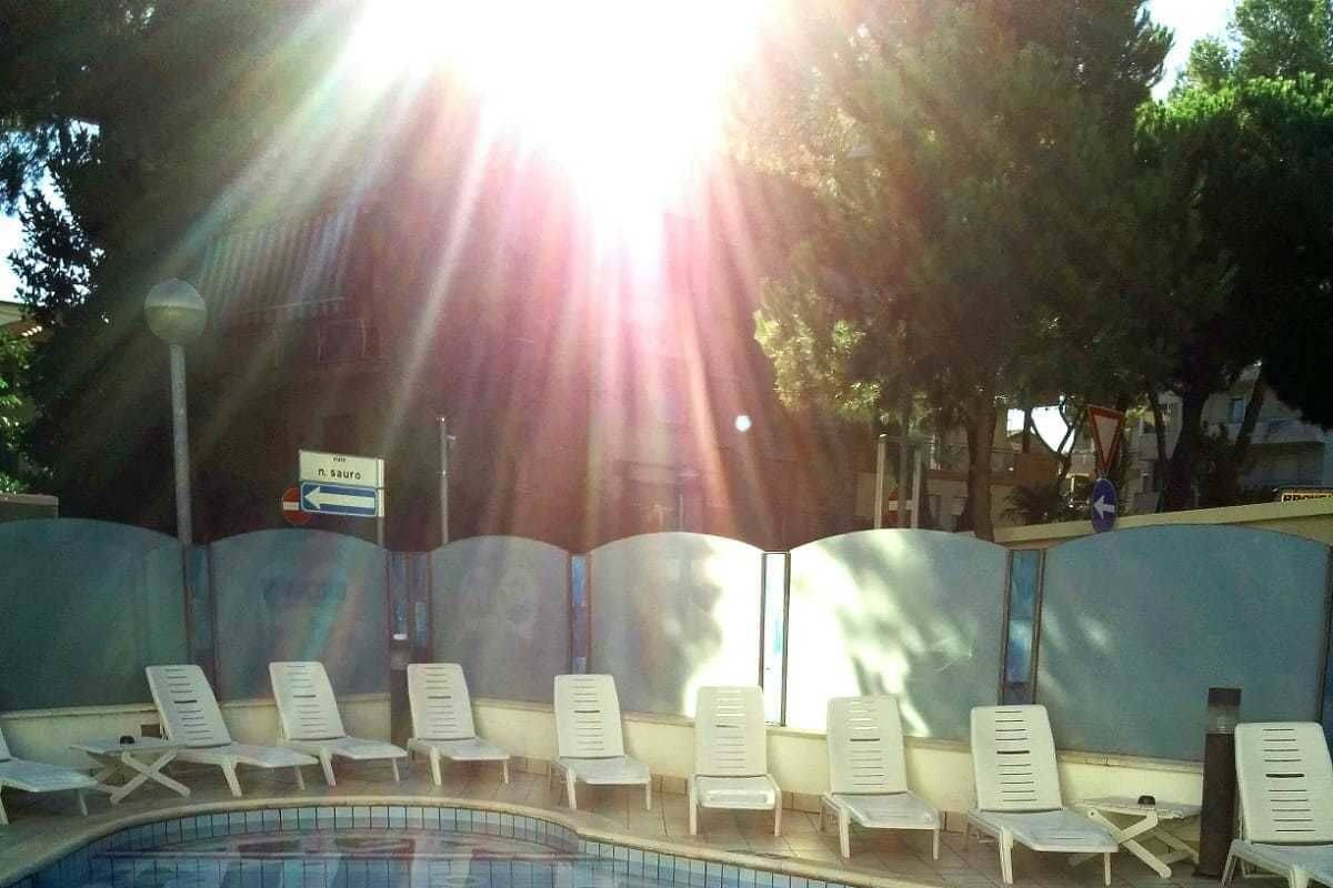 Una piscina con suelo de baldosas y sillones blancos alrededor.