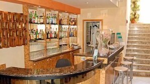 Angolo bar con bancone curvo, sgabelli e scaffali pieni di bottiglie.