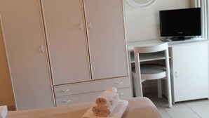 Una camera d'albergo con un letto, una scrivania, una televisione e un armadio.
