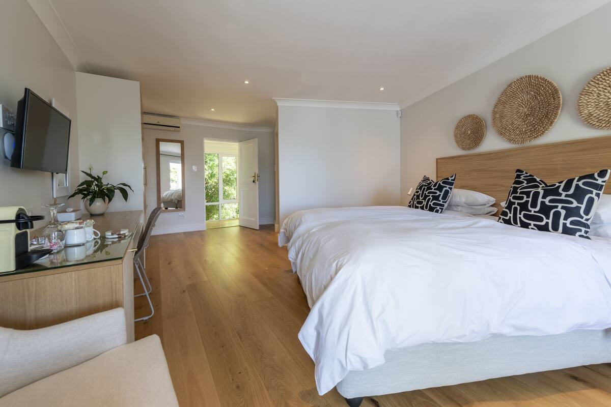 A modern bedroom with a large bed, bedside tables, a desk, and a television.
