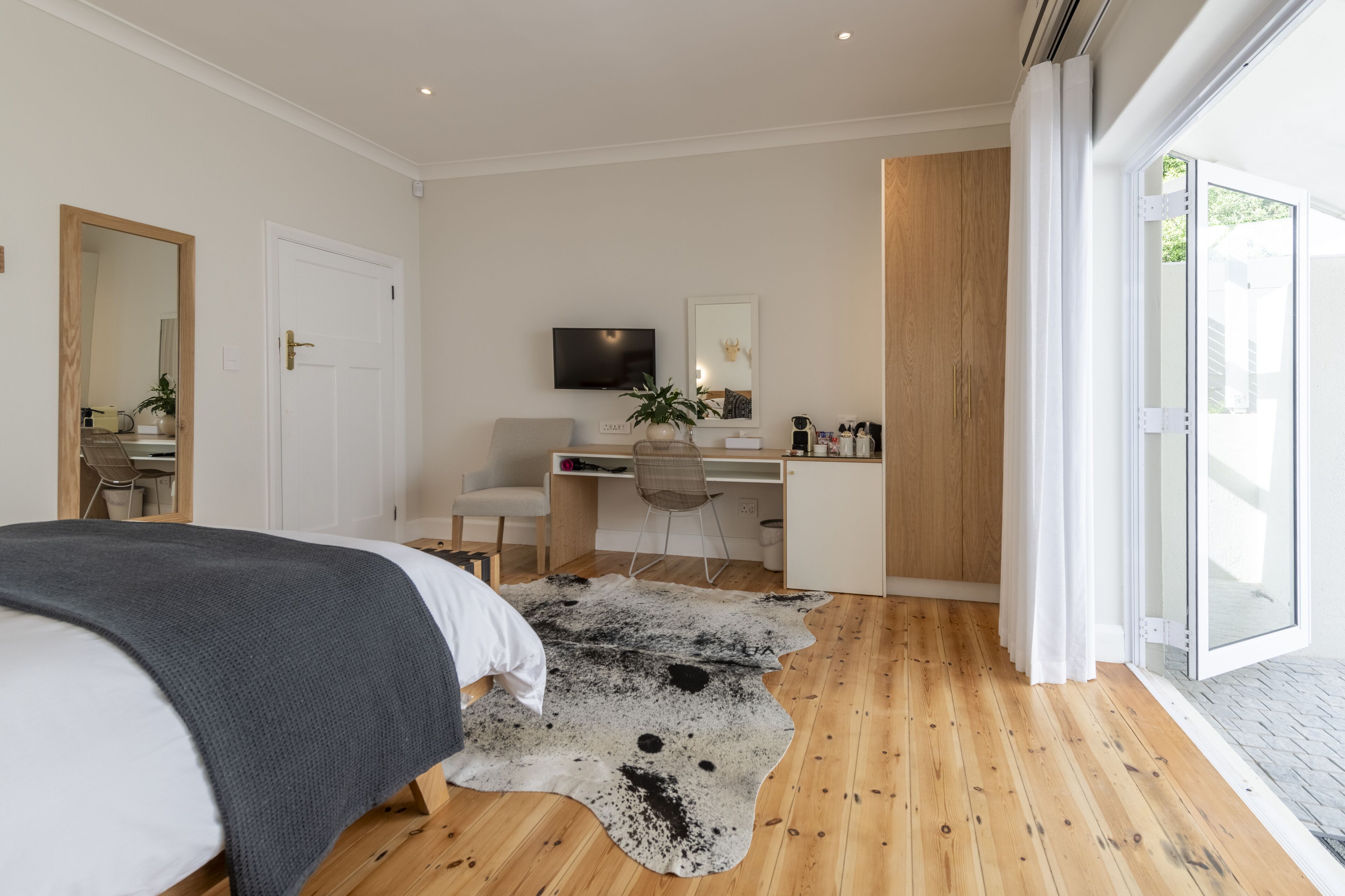 Un dormitorio con cama, escritorio, silla, televisión y un amplio ventanal.