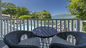 A balcony with wicker furniture and a view of a swimming pool and hills. - Hide Away Guest House (Knysna)