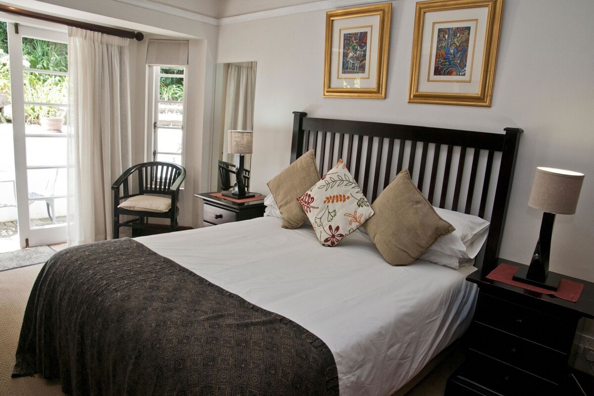 A hotel room with a bed, a chair, a nightstand, and a lamp.