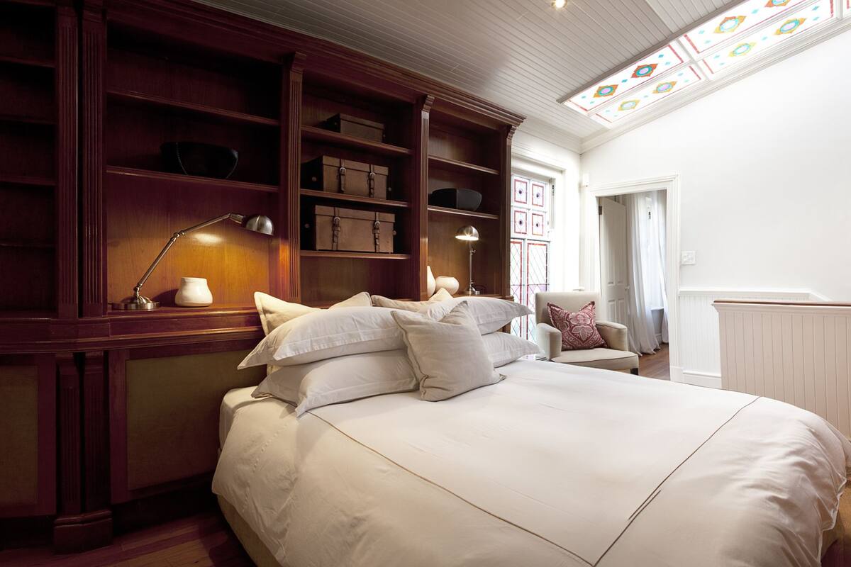 A bedroom with a large bed, wooden shelving, a desk, and a chair.