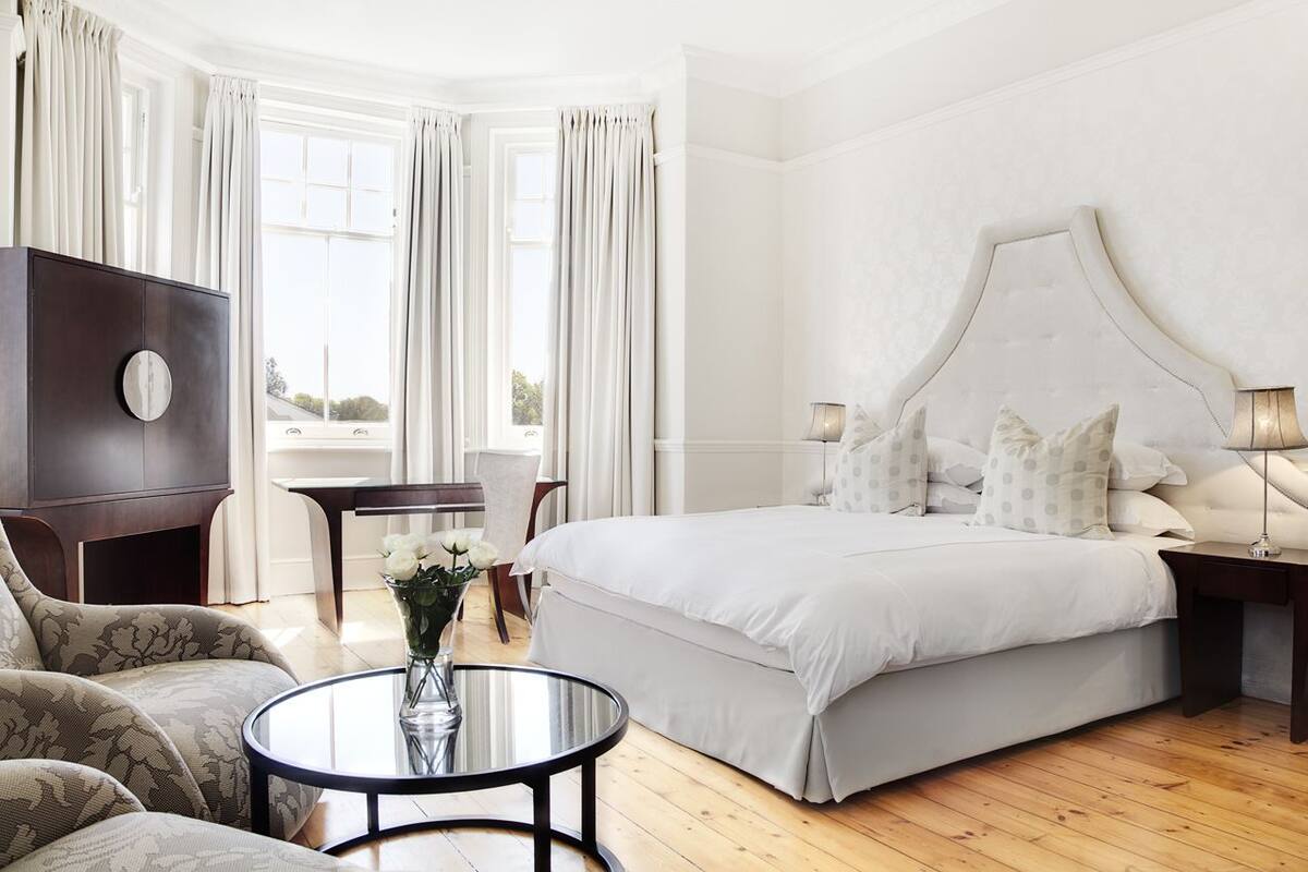 A hotel bedroom with a large bed, a round table, a sofa, and a TV.