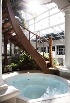 A wooden staircase leading to a glass-enclosed area with a hot tub.