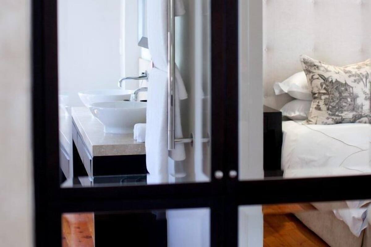 A modern bathroom with a large mirror, a white sink, and a white toilet.