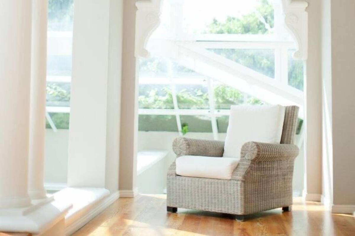 A room with a large arched window, a wicker chair, and a wooden floor.