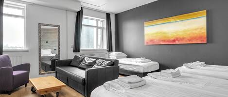 Una habitación de hotel moderna con una cama grande, un sofá, una silla y una mesita.