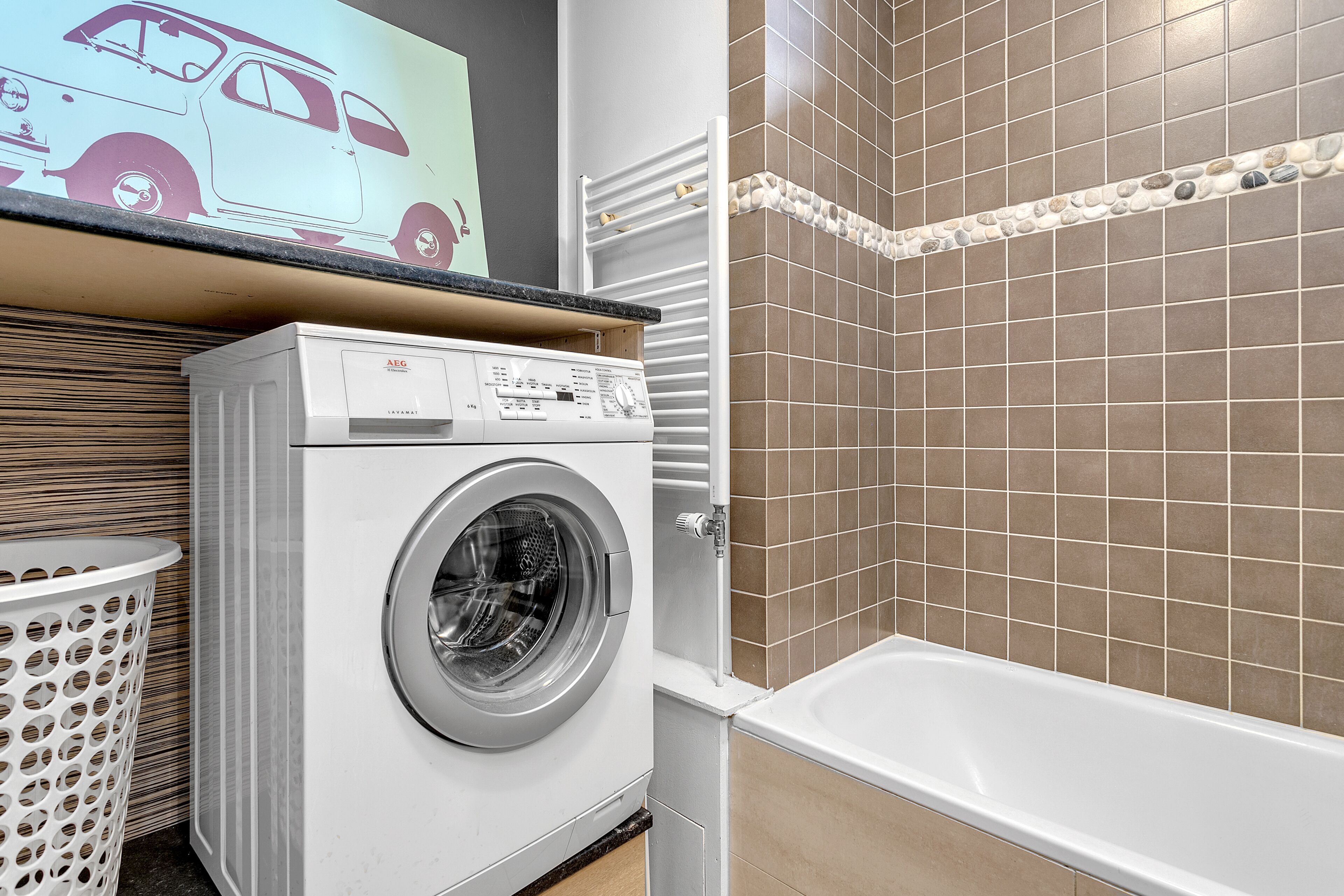 A laundry area with a washing machine, a drying rack, and a tub.