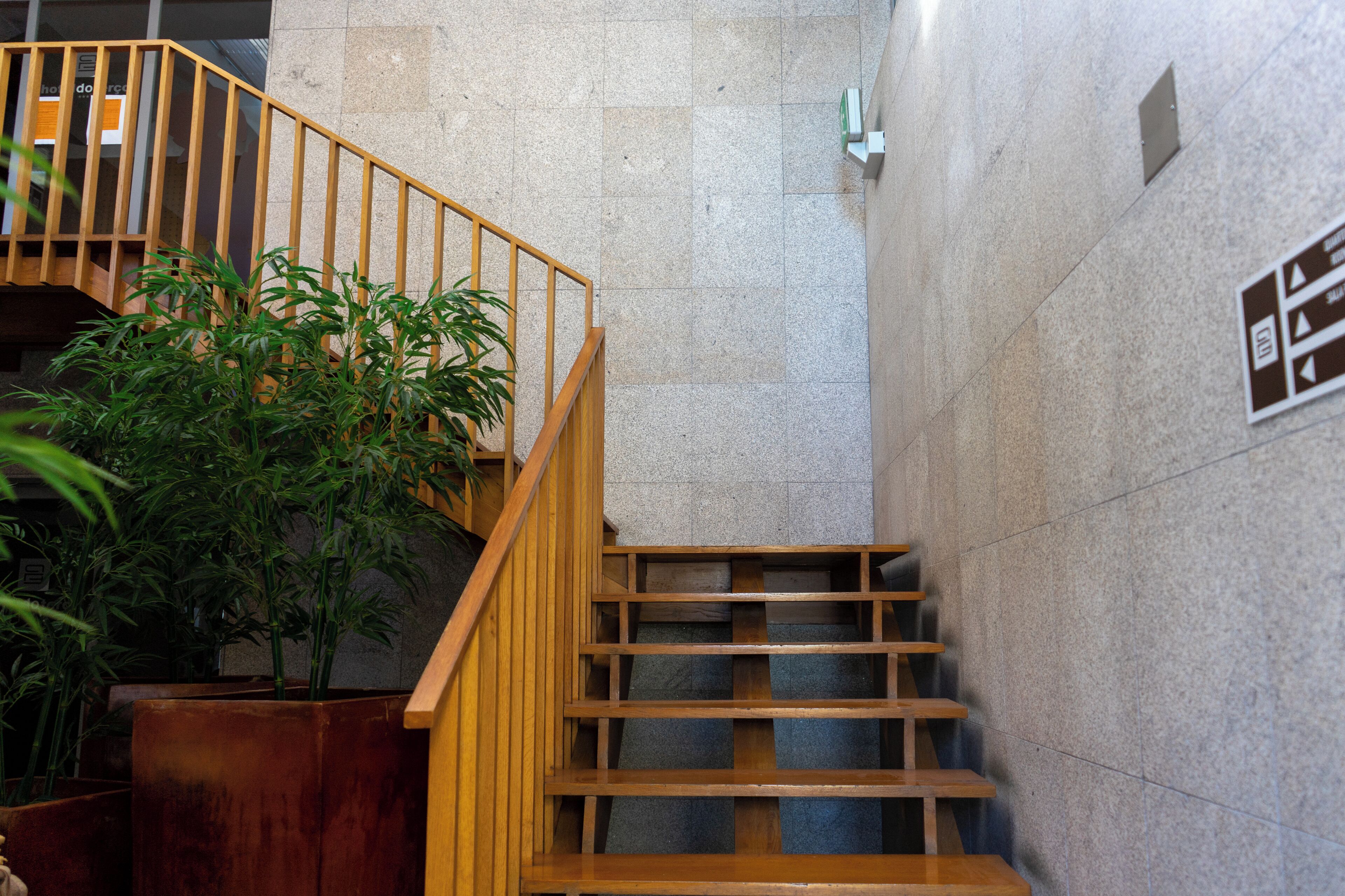 A staircase with wooden railings and a potted plant beside it.