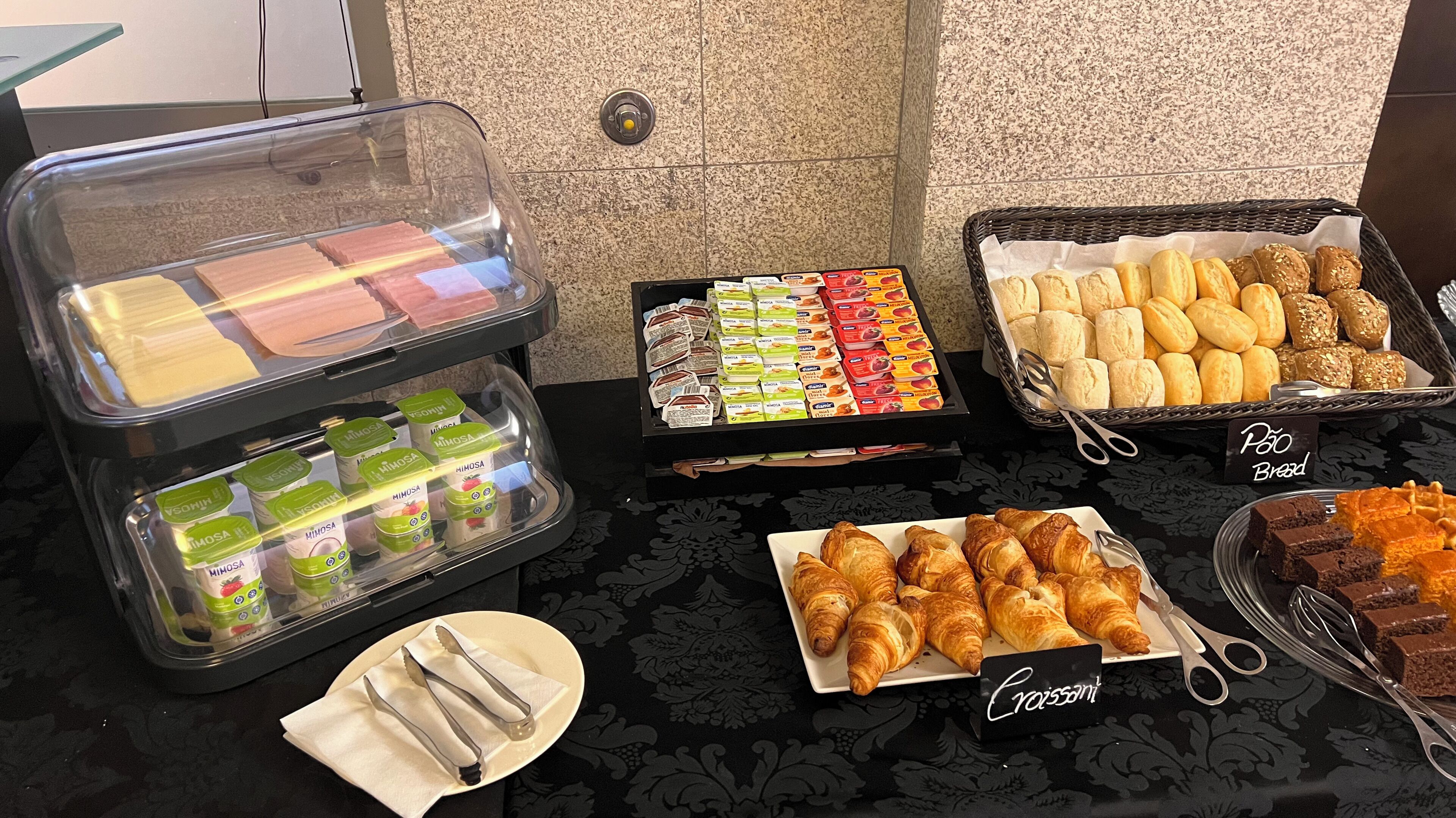 Un bufé con diferentes opciones de comida, incluyendo pasteles, pan y bocadillos envasados.