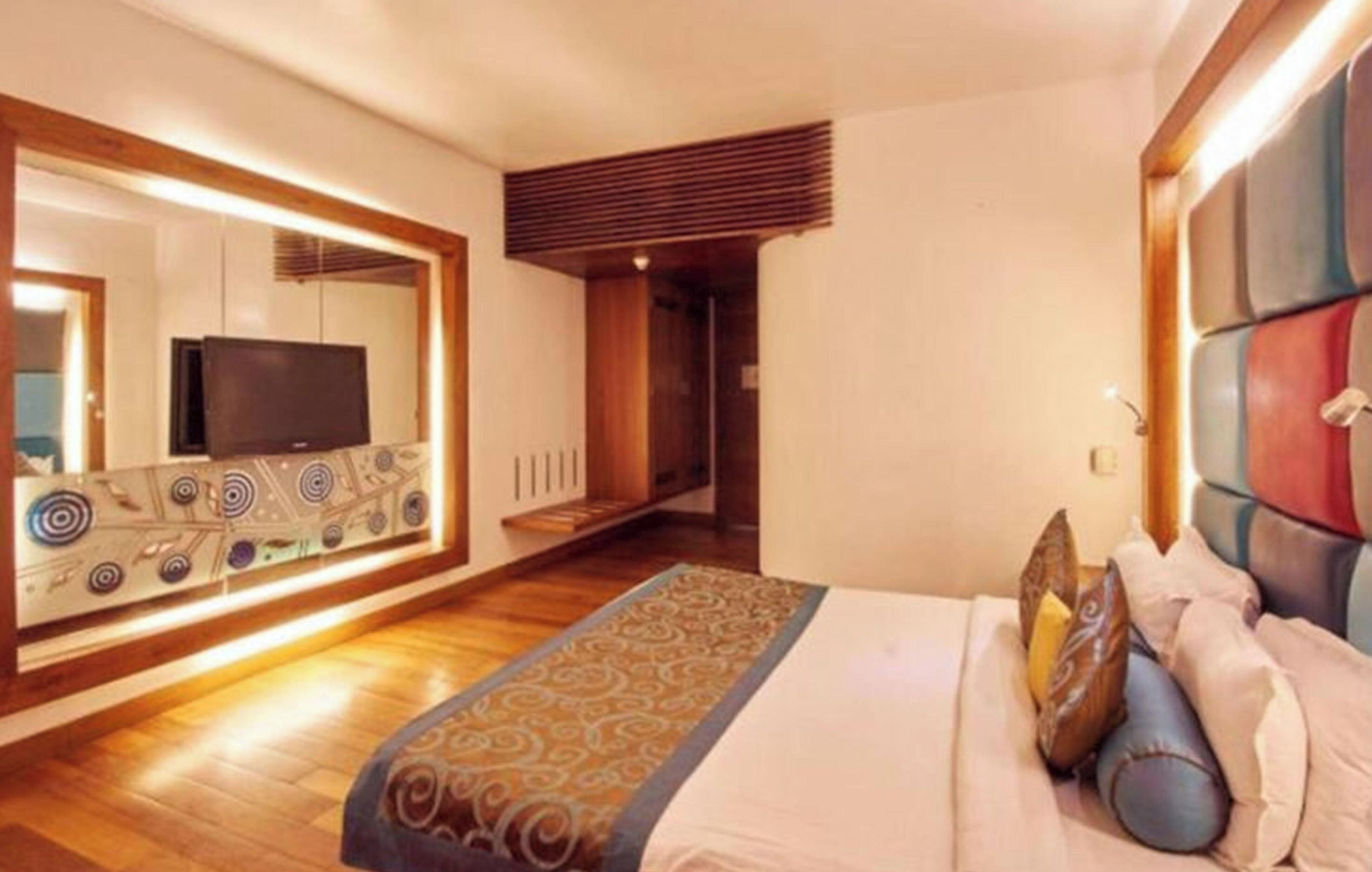 A hotel room with a large bed, a television, and a decorative wall unit.