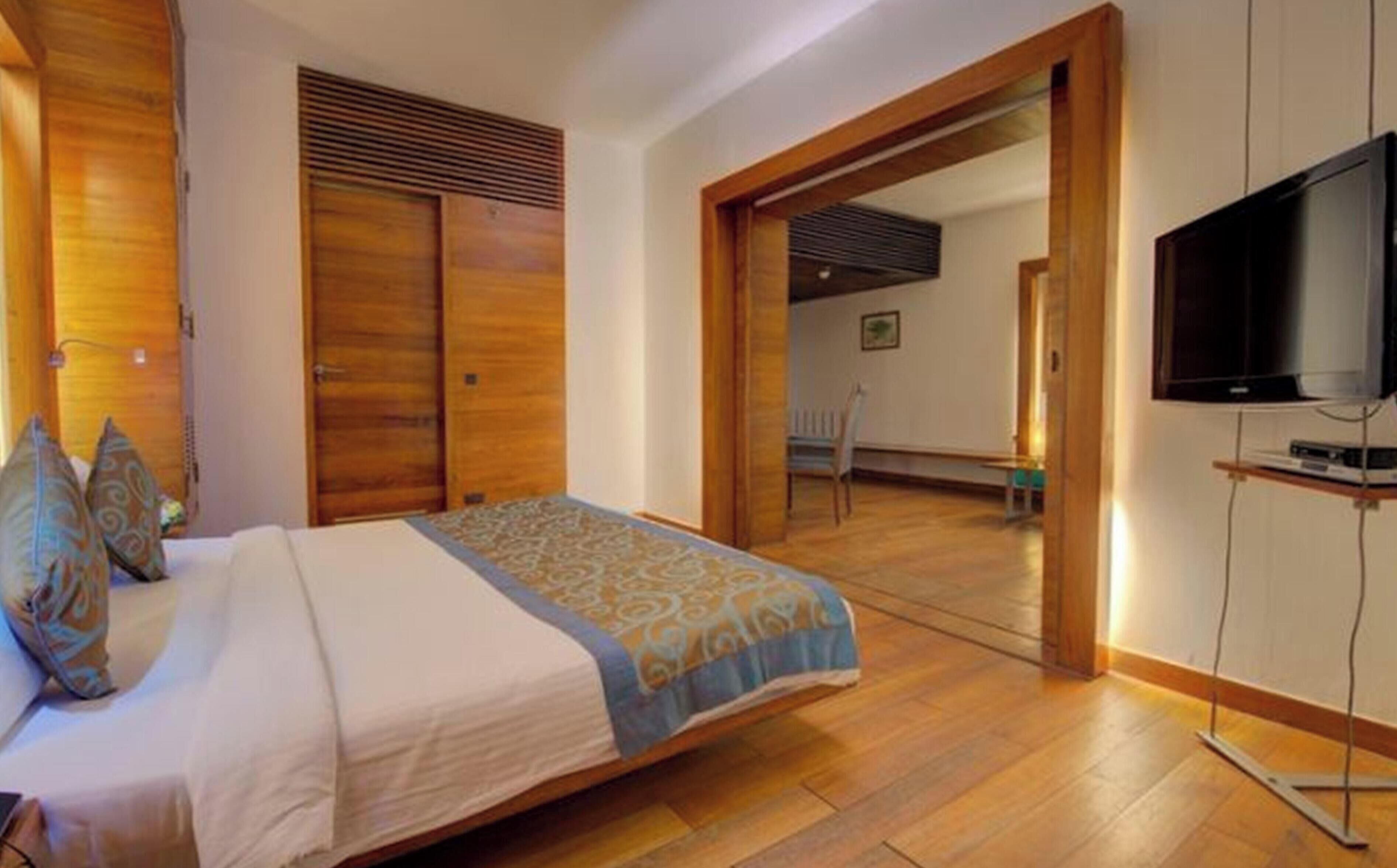 A bedroom with a bed, wooden wardrobe, and a television.