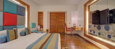 A hotel room with a large bed, a desk, a television, and a mirror.