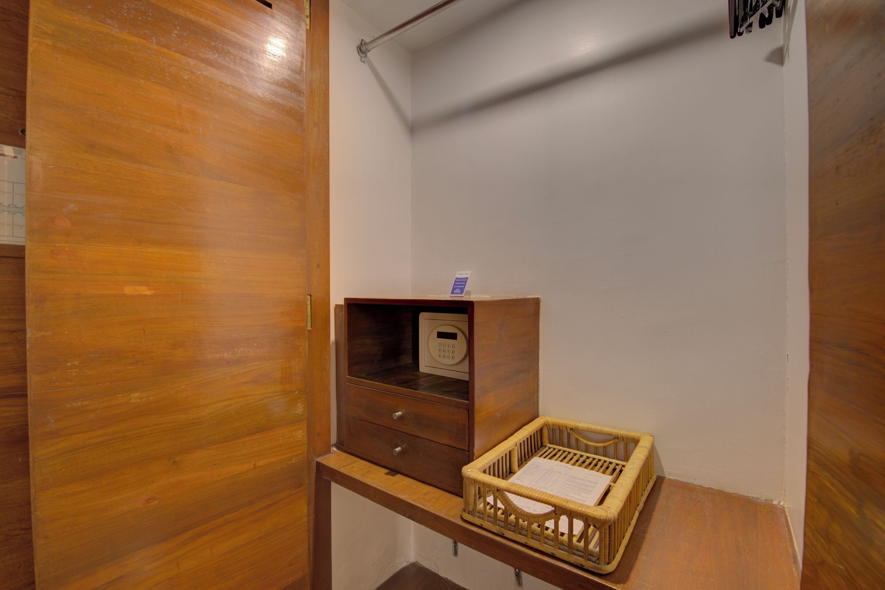 Un piso de madera, un pequeño armario de madera con un dispositivo digital y una cesta de mimbre sobre un banco de madera.