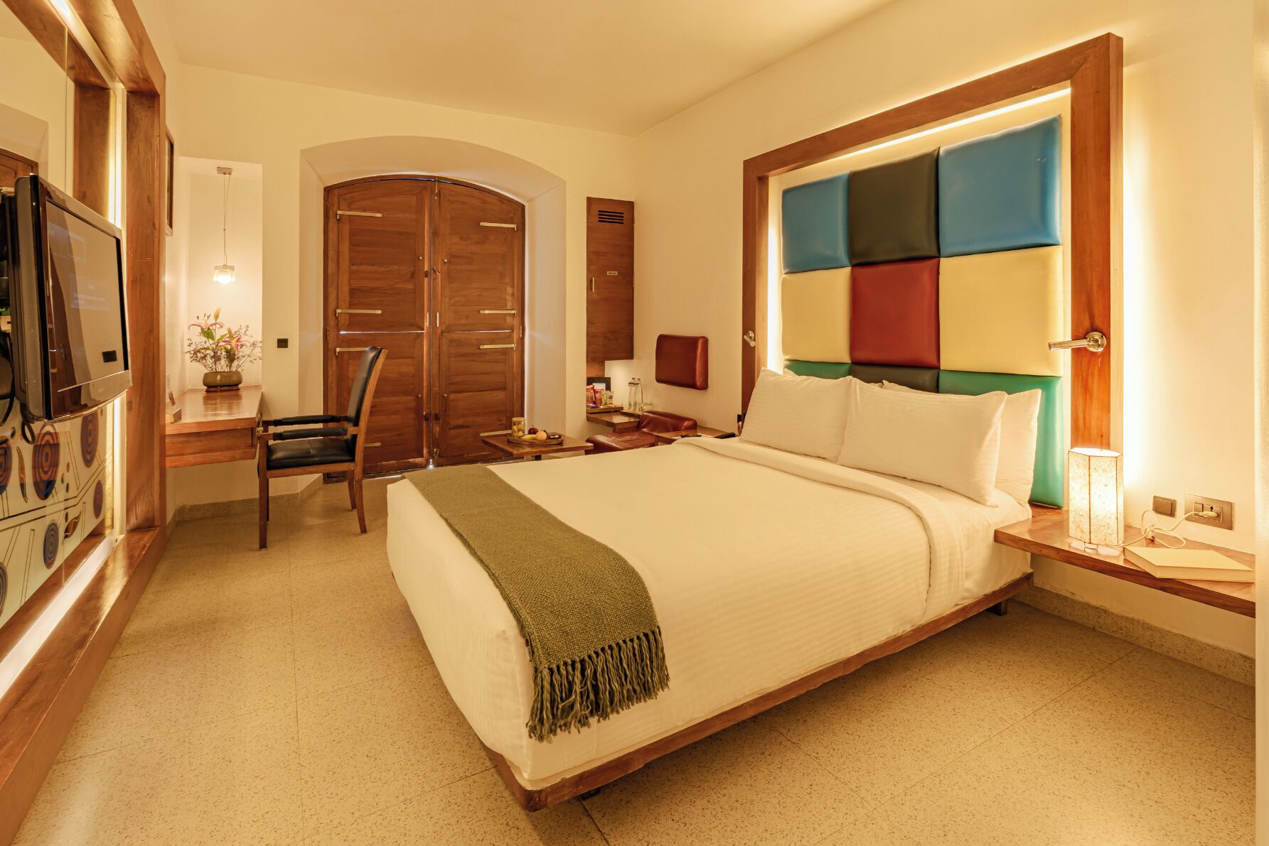 A hotel room with a bed, a desk, a chair, a TV, and a wardrobe.