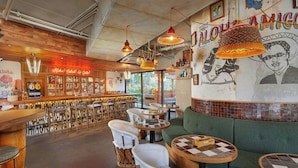 Un rincón de bar acogedor con muebles de madera, lámparas colgantes y un mural en la pared.