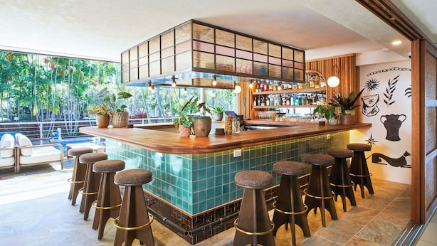 Un área de bar con una barra de madera, varios taburetes y vistas al exterior.