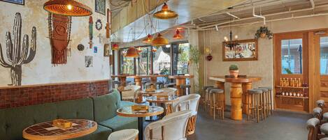 Un café acogedor con muebles de madera, sillas tejidas e iluminación colgante.