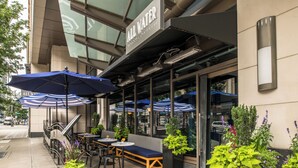 An outdoor seating area with umbrellas, tables, and a bench at a restaurant.