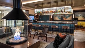 A bar area with a glass enclosure, seating, and a bar stocked with bottles.