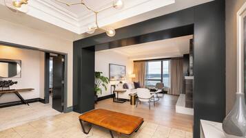 Una habitación de hotel moderna con un gran ventanal, una zona de estar y una mesa de comedor.