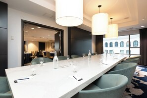 A conference room with a long table, chairs, and overhead lighting.