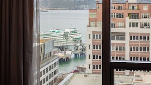 A room with a large window overlooking a waterfront, a chandelier, and a view of a building across the water.
