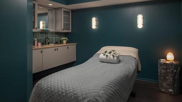 A bedroom with a bed, a nightstand with a lamp, a window, and a bathroom with a sink and cabinets.