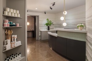 A modern kitchen with a curved island, built-in shelves, and a potted plant.