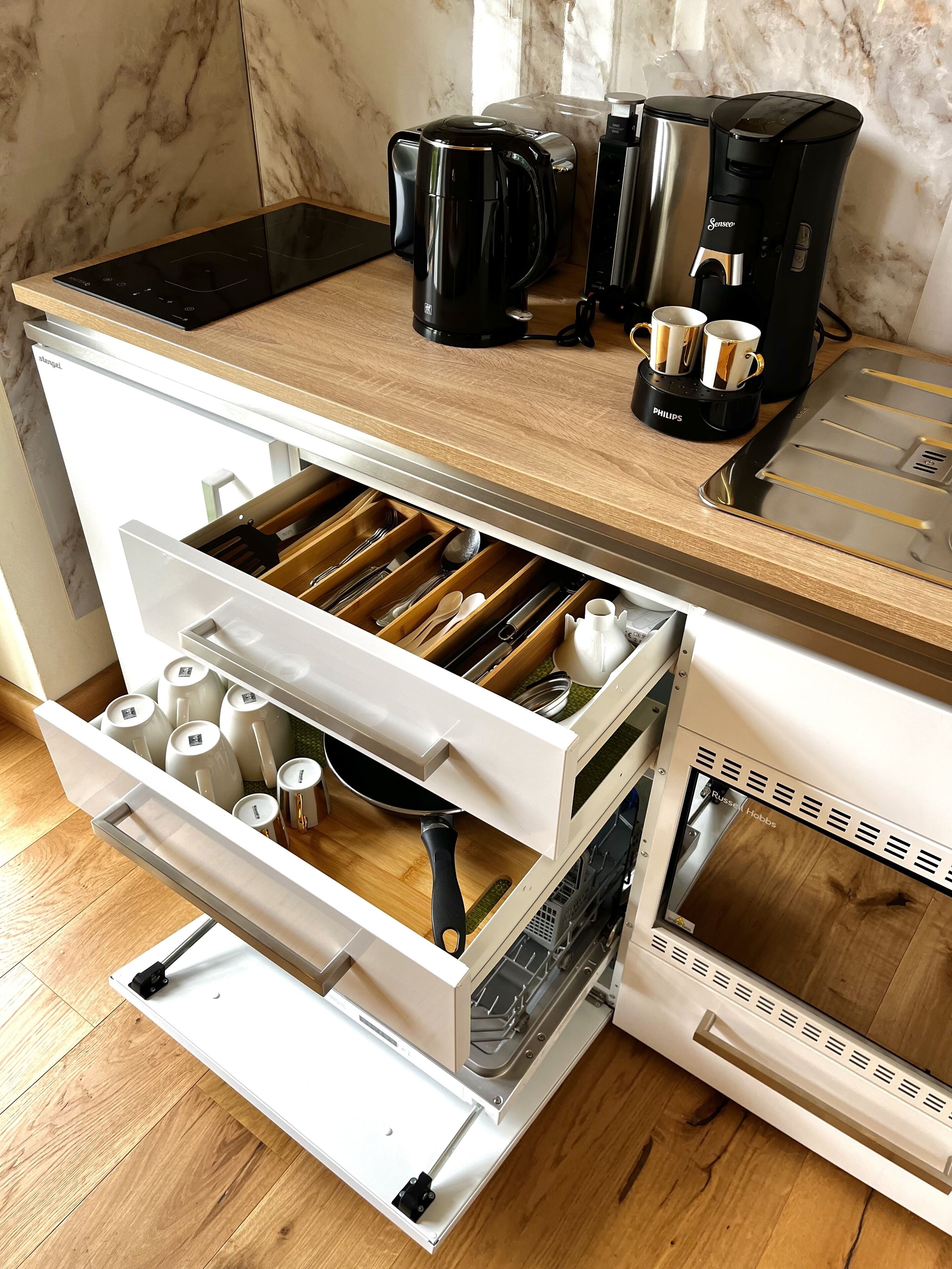 Une cuisine  équipée d’un lave-vaisselle intégré, d’une machine à café et d’un organiseur de tiroir.