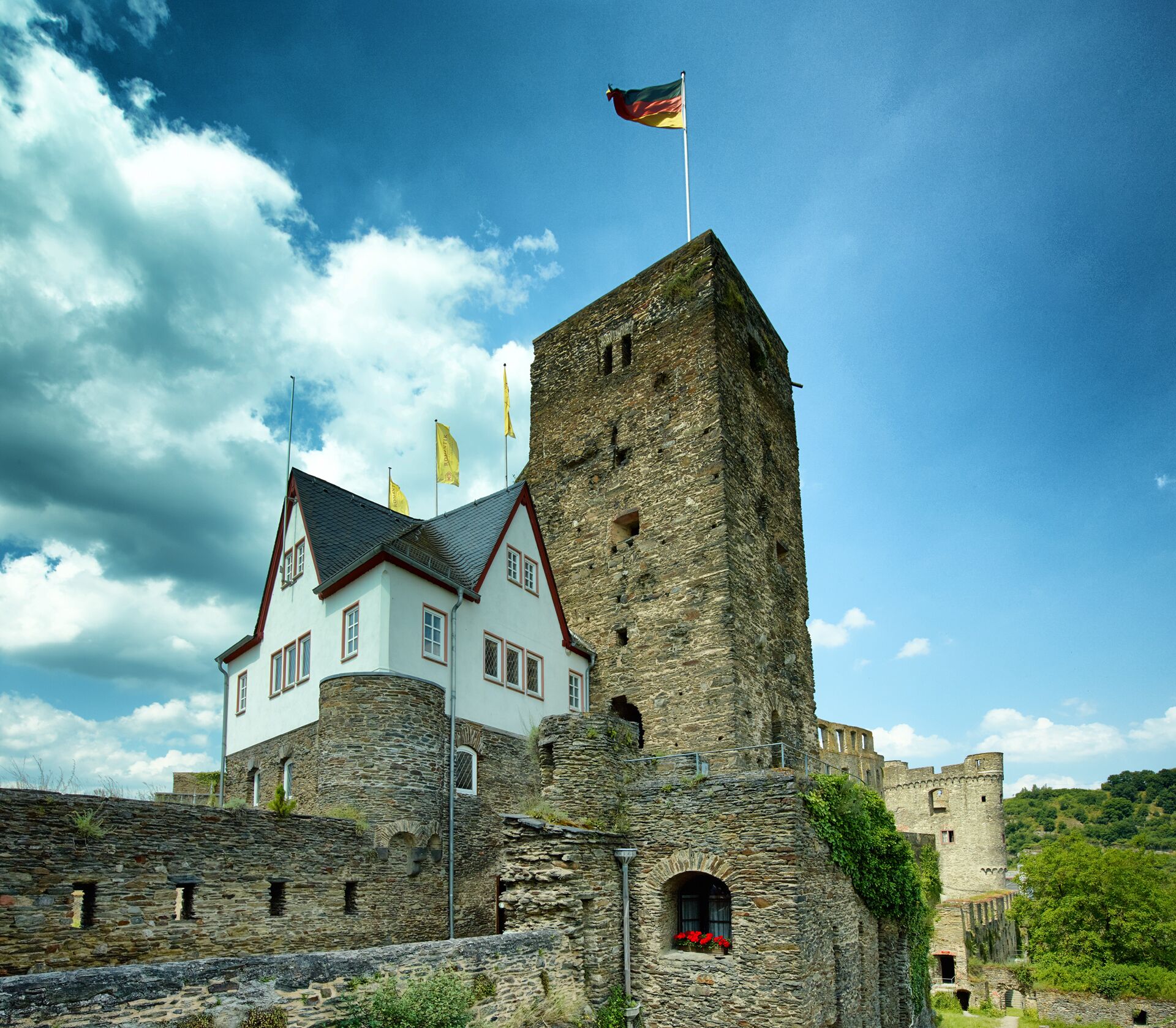 A historic building with a stone tower and a white building with red trim.