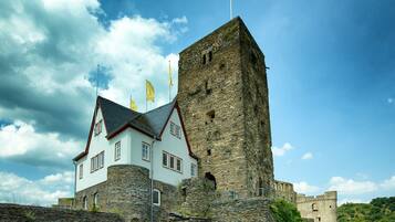 A historic building with a stone tower and a white building with red trim.