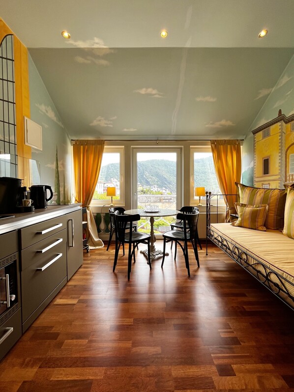 Una cocina moderna con comedor, ventanas grandes con cortinas y vistas a las colinas.