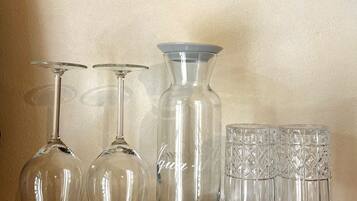 A marble-tiled countertop with a glassware set including wine glasses, a decanter, and a set of glasses.