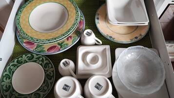 A drawer containing various white ceramic dishes, including plates, bowls, and cups, with decorative patterns.