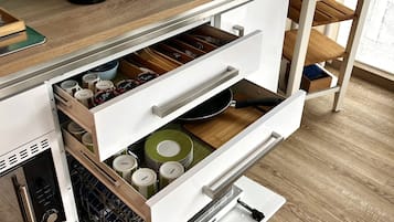 Eine Küche mit Kaffeemaschine, Topf und einer Schublade voller Kochutensilien.