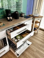 Eine Küche mit Kaffeemaschine, Topf und einer Schublade voller Kochutensilien.