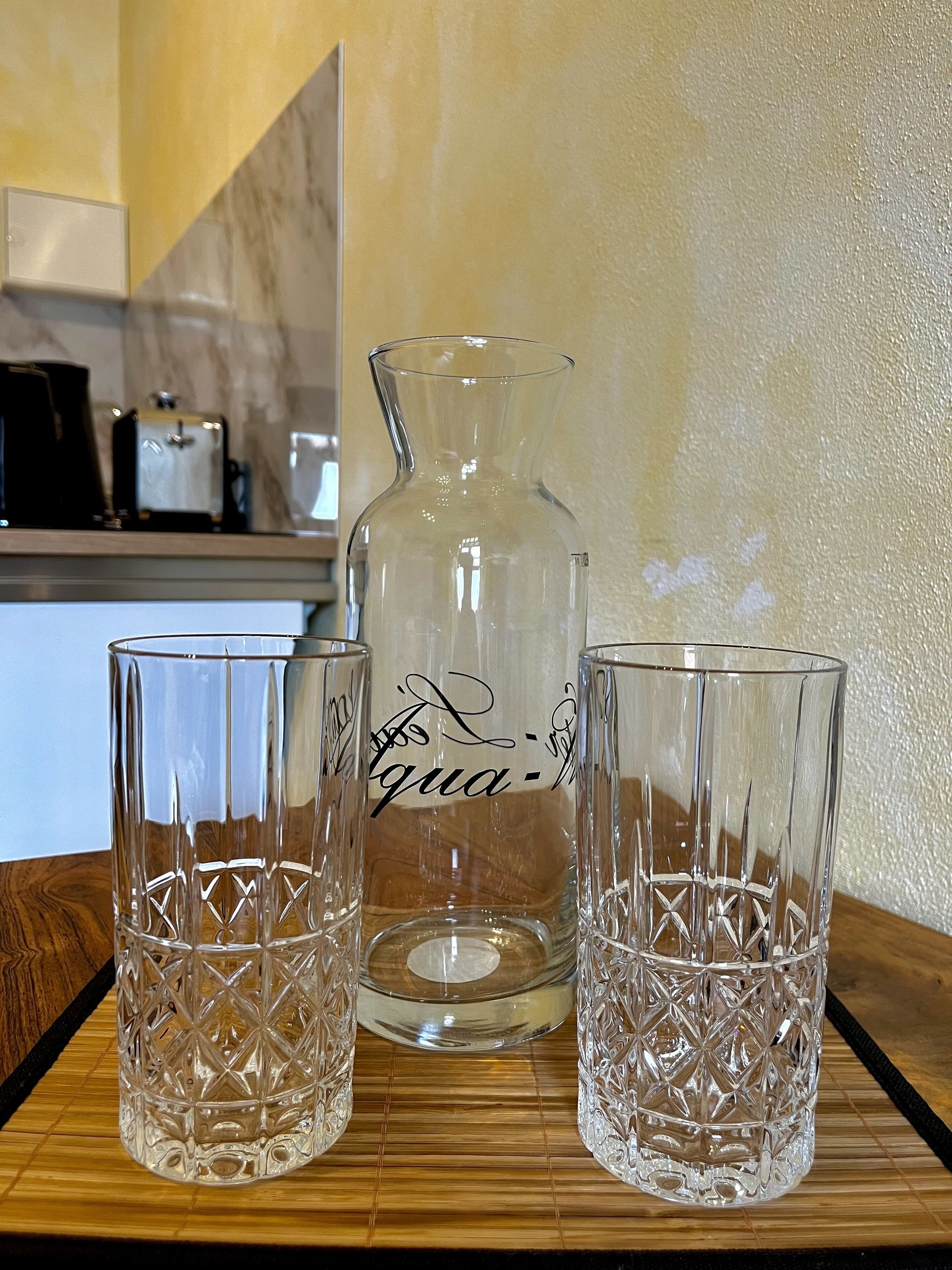 Una encimera de cocina con una jarra transparente y dos vasos.