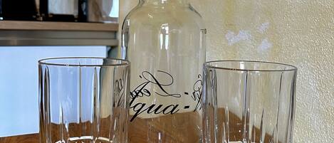 Una encimera de cocina con una jarra transparente y dos vasos.