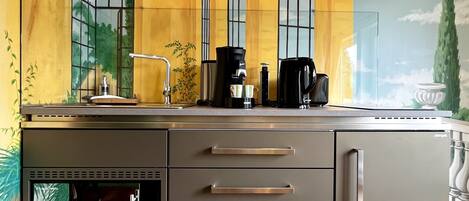Una cocina moderna con horno empotrado, cafetera y lavaplatos.
