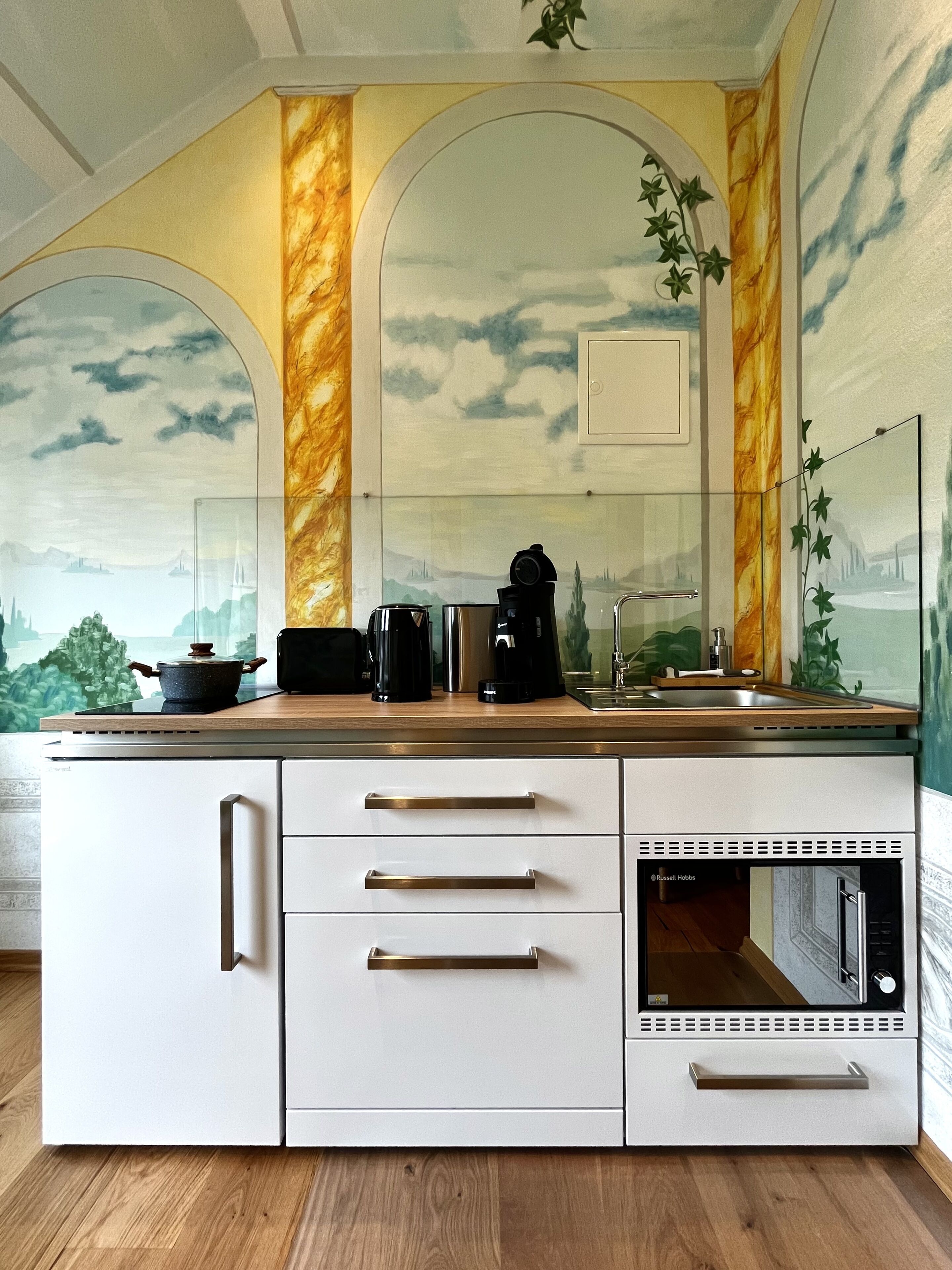 Una cocina de diseño moderno, con salpicadero de mármol, un ventanal grande y un microondas integrado.