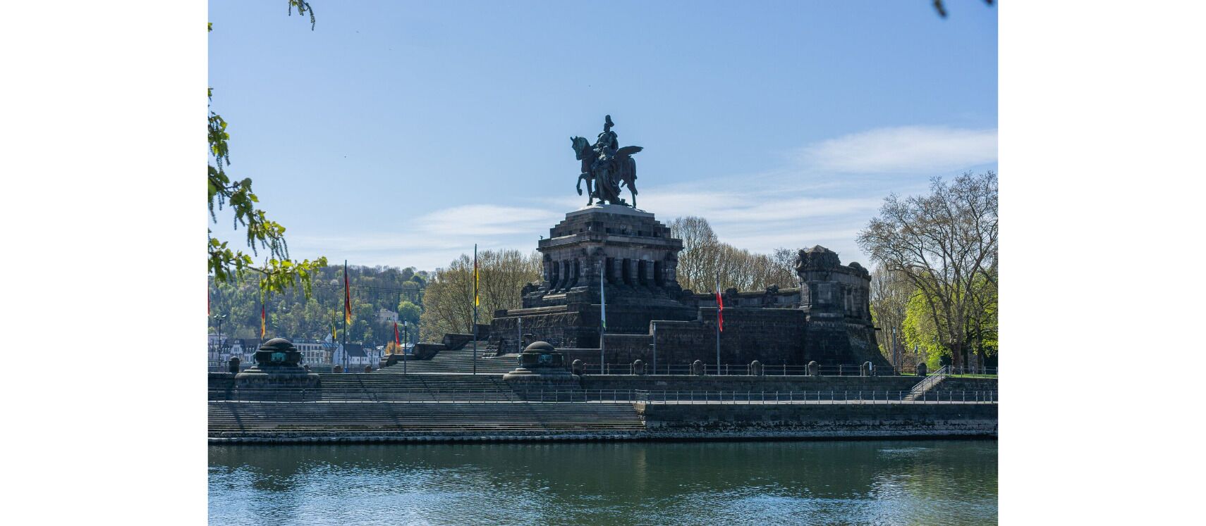 A historical monument with a statue on top, surrounded by steps and a body of water in the foreground.