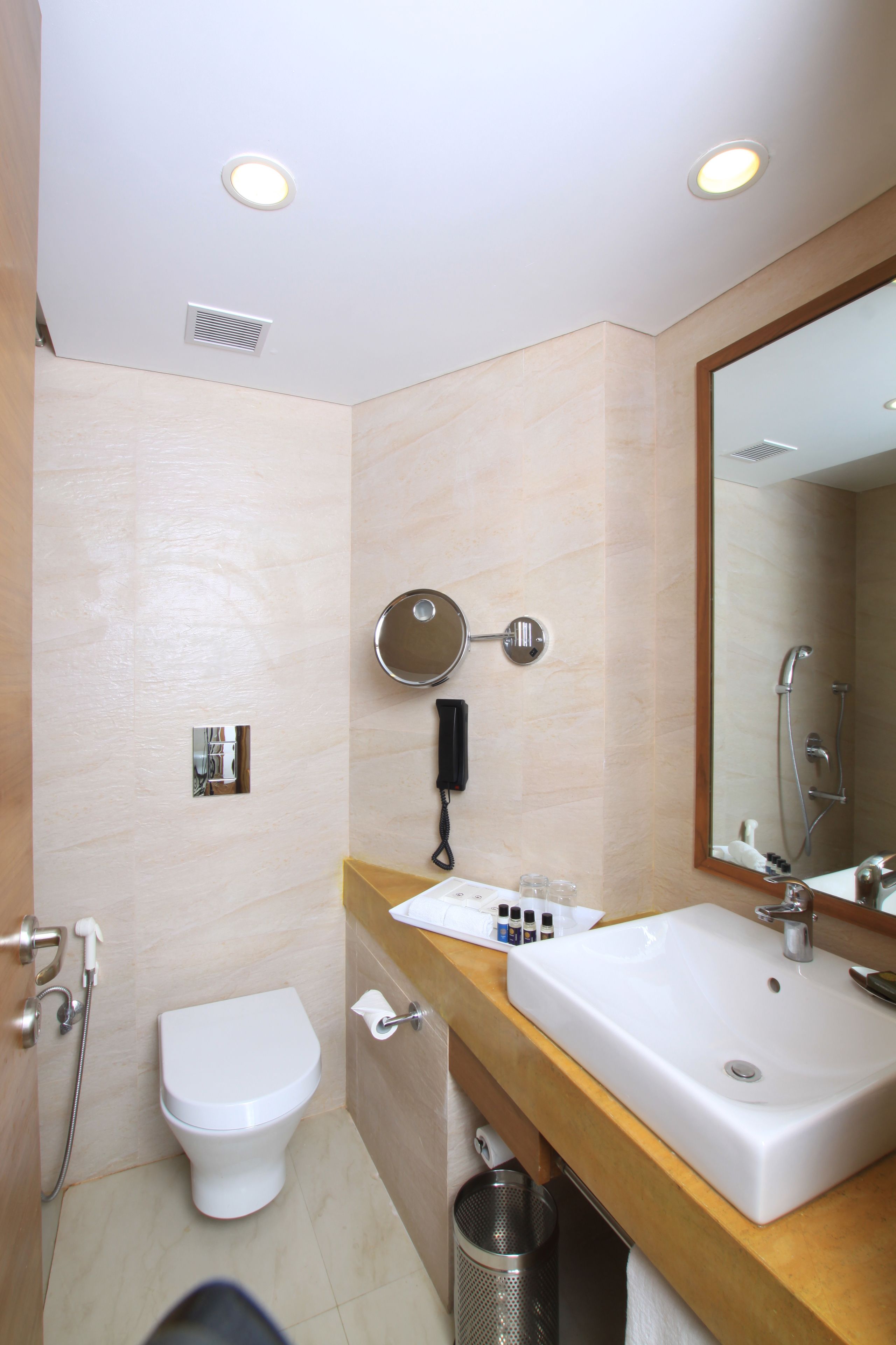 Un baño moderno con inodoro blanco, lavamanos con espejo y ducha.